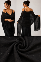 Load image into Gallery viewer, A black sheer off-the-shoulder shawl or wrap shown on a model from the front and back, with a close-up fabric detail panel at the bottom showing a subtle shimmering texture and small reflective embellishments.