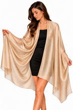 Load image into Gallery viewer, A woman modeling a shimmering champagne-gold draped shawl or wrap over a black dress, shown against a plain white studio background.