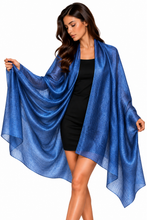 Load image into Gallery viewer, A woman modeling a sheer, lightweight royal blue wrap or shawl draped over her shoulders, worn over a black dress, against a solid white background.