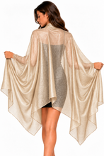 Load image into Gallery viewer, A woman wearing a sheer, metallic champagne-colored cape-style poncho over a gray dress, shown from the back against a plain white background.