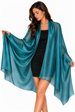 Load image into Gallery viewer, A woman modeling a sheer, flowing teal-blue shawl or wrap draped over a black dress against a plain white background.