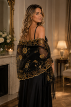 Load image into Gallery viewer, A woman in a black dress is shown from the back in an elegant room, wearing a sheer black shawl with ornate gold floral embroidery and fringe.