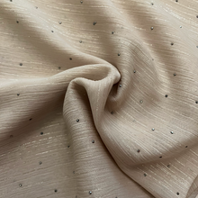 Load image into Gallery viewer, A close-up of a draped beige fabric with a subtle crinkled texture and small scattered dark metallic dot embellishments.