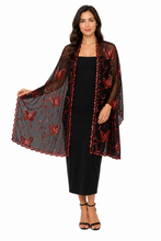 Load image into Gallery viewer, A woman modeling a sheer black mesh shawl with red embroidered butterflies and scalloped edges over a black midi dress, set against a plain white background.