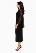 Load image into Gallery viewer, A woman shown in side profile wearing a black sheer lace top with scalloped edges over a black midi dress, paired with black heeled sandals, against a plain white studio background.
