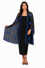 Load image into Gallery viewer, A woman modeling a sheer black mesh shawl with blue sequined butterfly patterns and scalloped edges, worn over a black midi dress against a plain white background. Pashmina for weddings, perties and evening dresses