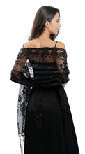 Load image into Gallery viewer, A woman shown from the back wearing a black off-the-shoulder sheer lace shawl draped over a black dress against a plain white background.