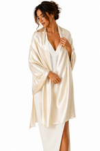 Load image into Gallery viewer, A woman wearing a shiny ivory satin shawl over a white dress, photographed against a plain white studio background.