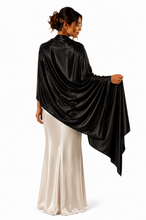 Load image into Gallery viewer, A woman shown from the back wearing a draped black satin cape-style top over a cream satin dress, photographed against a plain white studio background.
