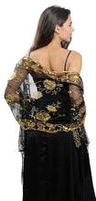 Load image into Gallery viewer, A woman shown from the back wearing a black off-the-shoulder dress with elaborate gold floral embroidery and sheer sleeves, paired with a black skirt.
